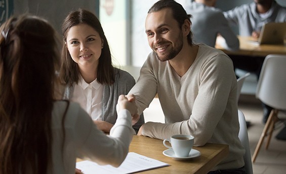 couple shaking hands with woman over coffee