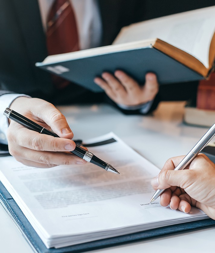 a man points out information on a document with a pen to a person signing the document